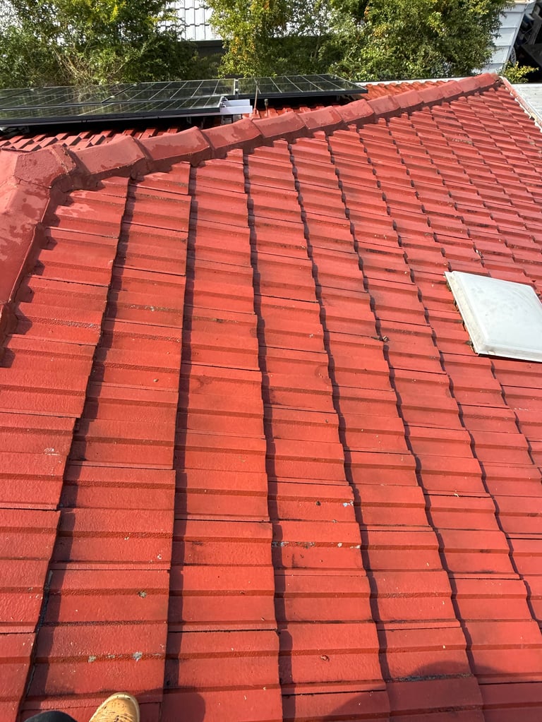 Red clay tile roof with grid patterns, solar panels visible in background, white vent cover on tiles